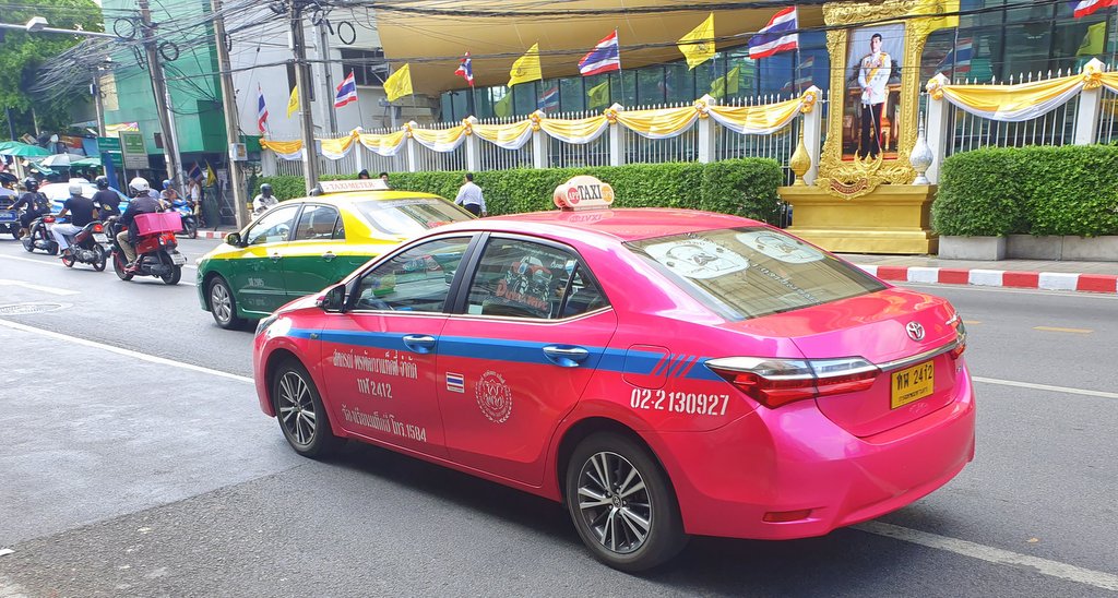 Pink taxi with a portrait of the king of Thailand in the background